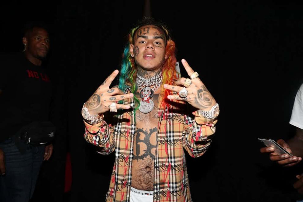 Tekashi 6ix9ine posing in open plaid button down shirt