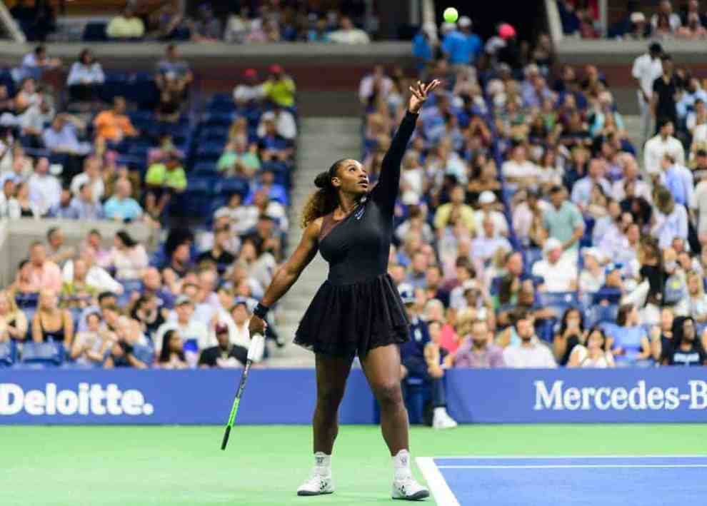 Serena Williams in all black outfit with off white tennis shoes