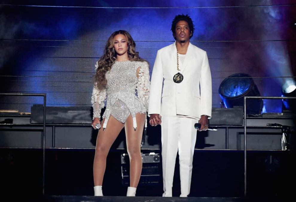 Jay-z and Beyonce holding hands on stage wearing all white