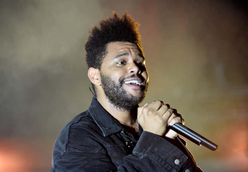 The Weeknd on Stage with a microphone in his hand
