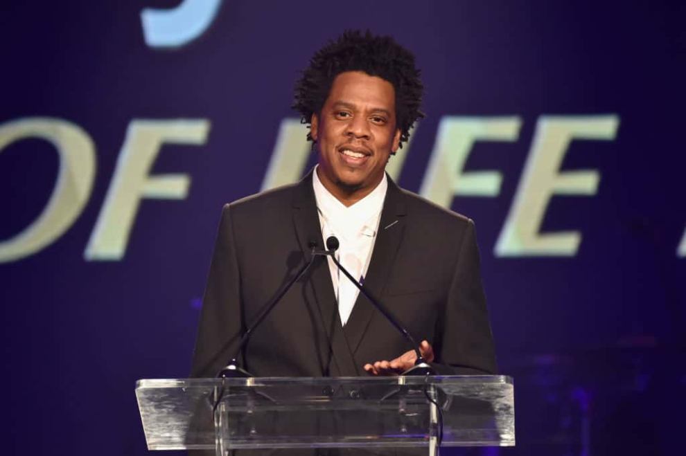 Jay-Z wearing black and white standing behind  a podium