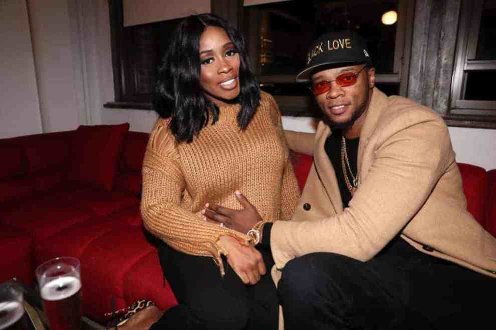 Remy Ma and Papoose wearing brown sitting on the couch