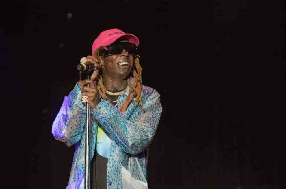 Lil Wayne on stage wearing a pink hat and sunglasses