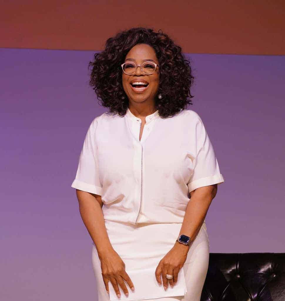 Oprah Winfrey smiling at the camera and wearing all white