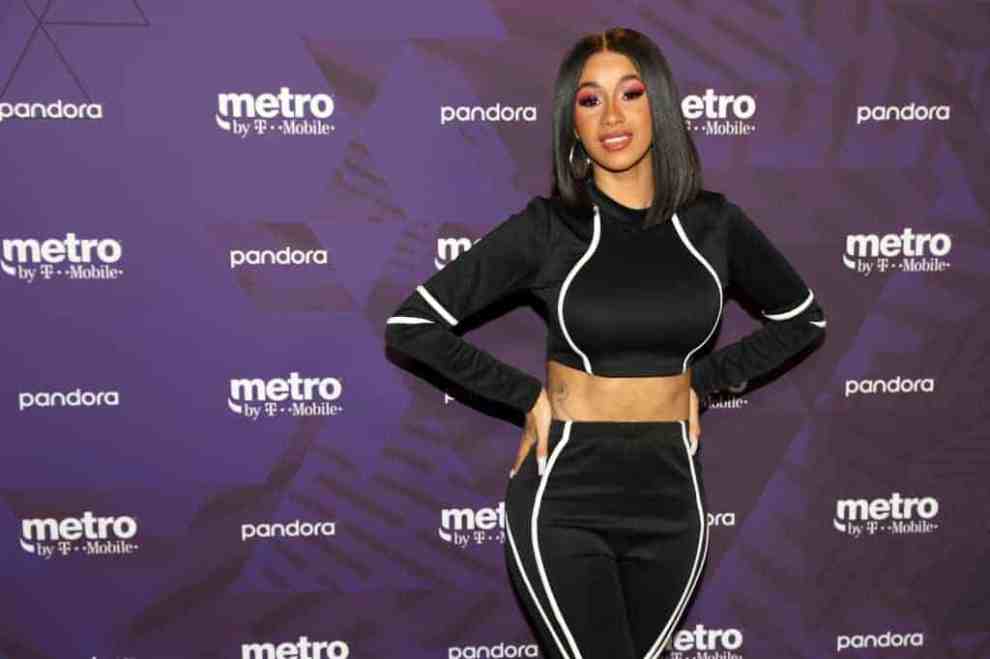 Cardi B standing in front of a purple back drop