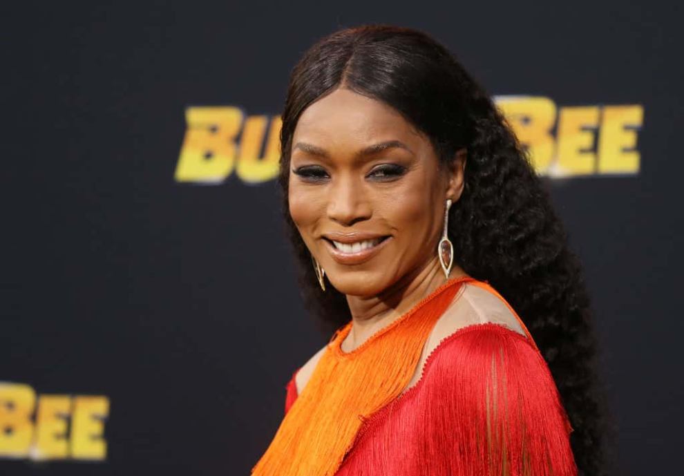 Angela Bassett wearing red and orange and facing the camera smiling