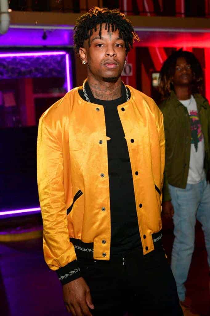21 Savage wearing a gold jacket and black shirt