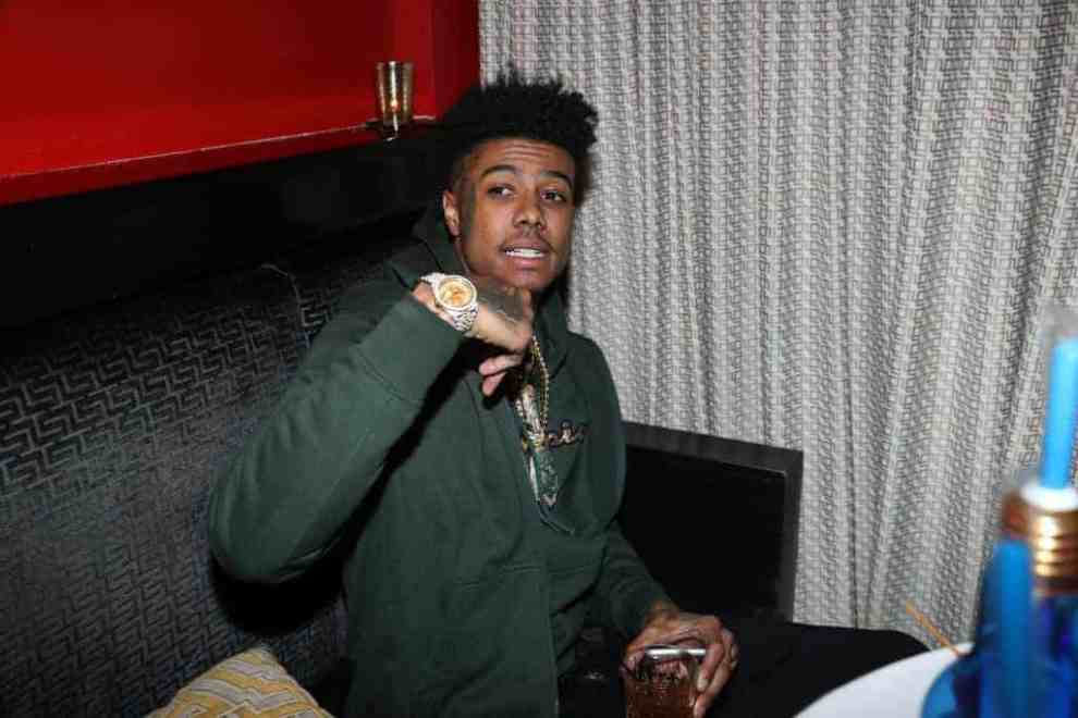Blueface sitting down with is hand up