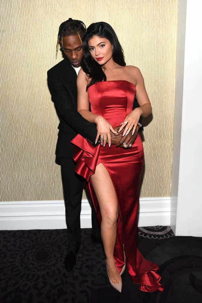 Kylie Jenner wearing a red dress and Travis Scott wearing a black tux