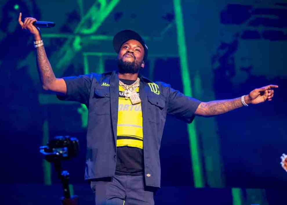 Meek Mill on stage performing wearing a yellow shirt and black shirt