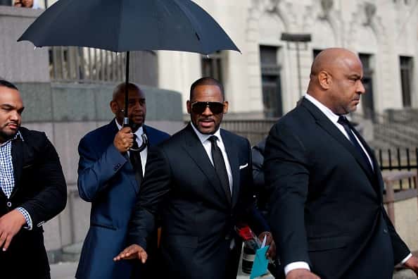 Music artist R. Kelly (C) waves as he holds a card and a rose he received from fans as he leaves the George N. Leighton Criminal