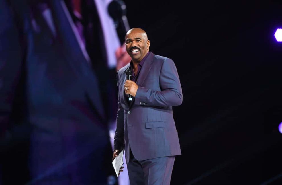 Steve Harvey wearing a purple suit on stage