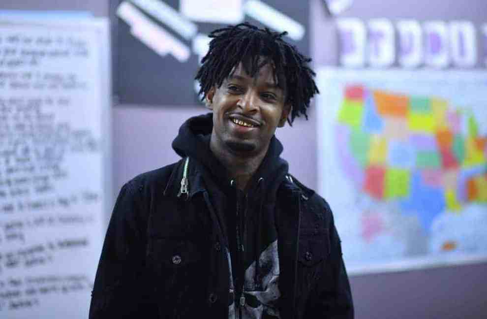 21 Savage wearing a black hoodie smiling
