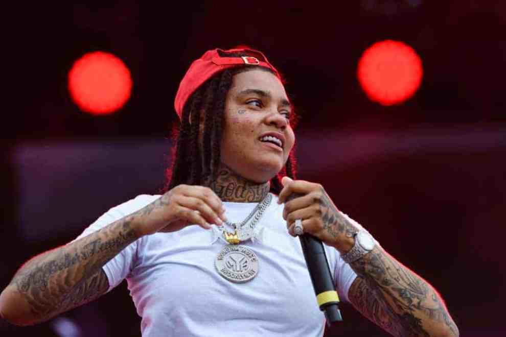 Young M.A on stage  wearing a white tee and red hat