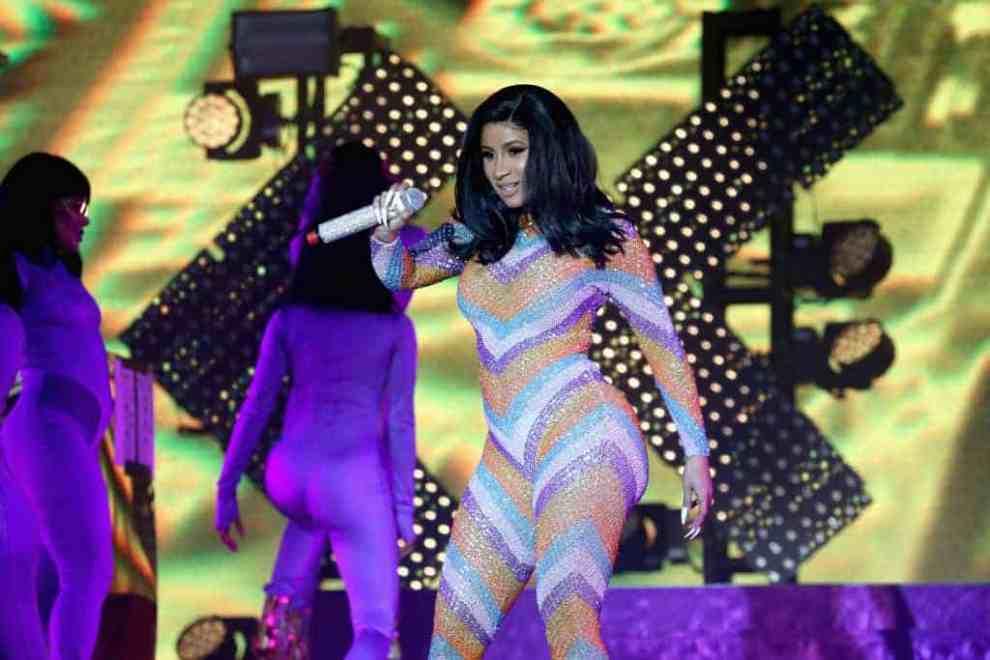 Cardi B on stage wearing a multi-colored one piece suit