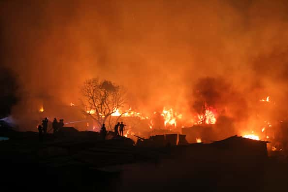 Firefighters with the help of locals work to douse a fire in a slum in Mirpur