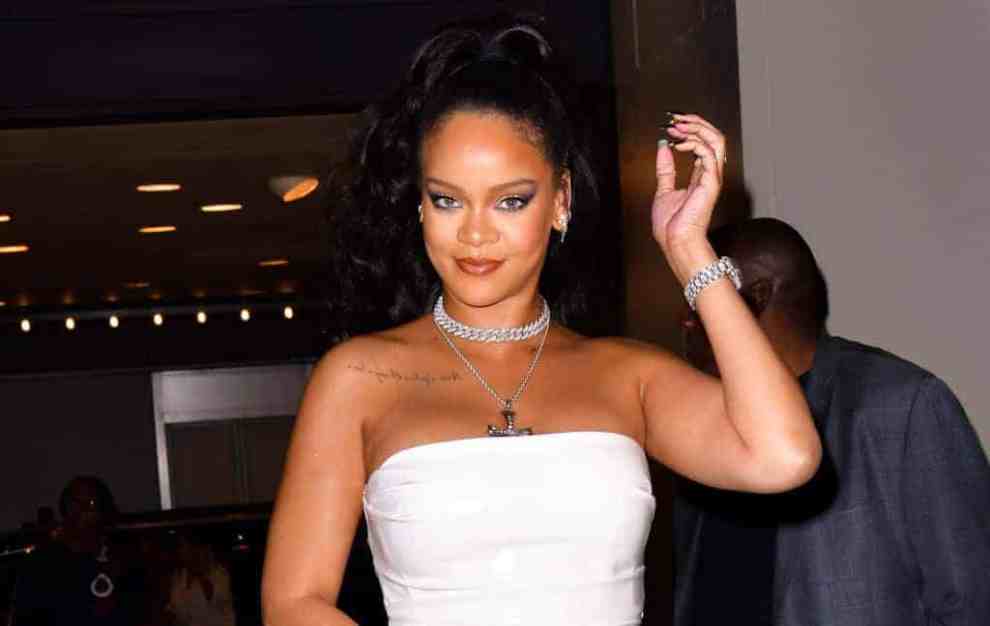 Rihanna wearing a white dress smiling at the camera