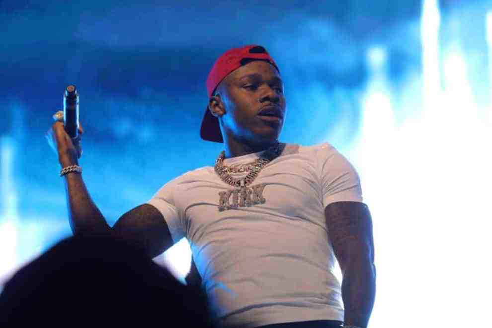 DaBaby on stage wearing white shirt and red hat