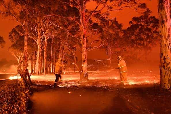 This timed-exposure image shows firefighters hosing down trees as they battle against bushfires around the town of Nowra in the
