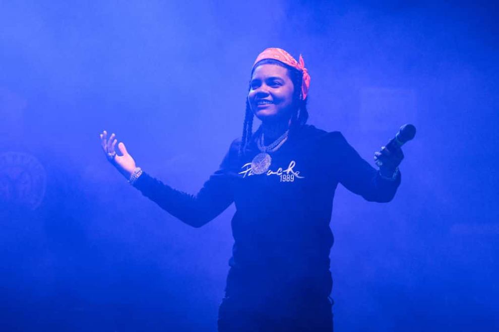 Young M.A wearing black on stage under a blue light