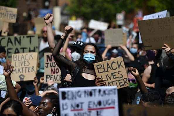 Demonstrators carry placards with slogans as they march near the US Embassy in London on May 31