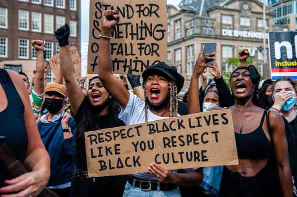 A black woman is screaming while holding a big placard