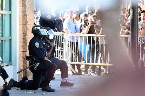 Police officers kneel after a crowd of protesters called for them to "take a knee" in front of a police station in San Francisco