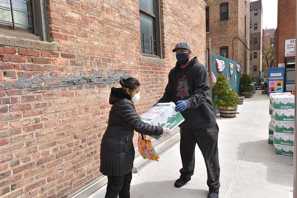 Former professional baseball player CC Sabathia (R) distributes pantry boxes to Boys And Girls Club families at the Belmont Community Day Care Center on April 08