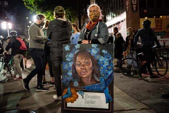 A demonstrator holds a painting of Breonna Taylor during a protest near the Seattle Police Departments East Precinct on June 7
