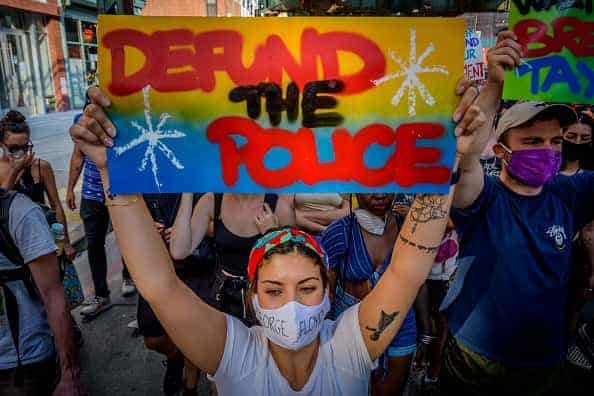 A New York City Police Department (NYPD) officer stands next to a vehicle parked outside the 1st Precinct in the Tribeca neighborhood of New York