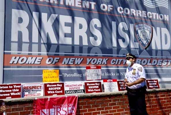 A correctional officer asks protesters during the nurses protest to not cover the main entrance with signs at Rikers Island Prison on May 7