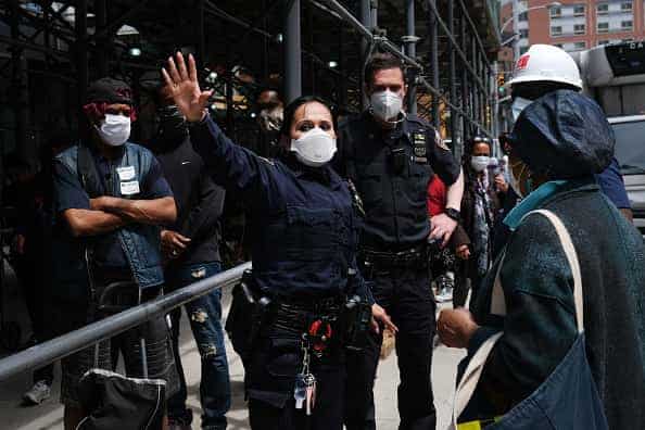 People are directed by police as over one thousand individuals wait in line at the Barclays Center in Brooklyn for a free food distribution on May 15