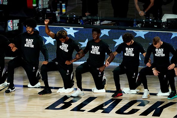Lance Thomas of the Brooklyn Nets gestures as he and teammates kneel in honor of the Black Lives Matter movement prior to an NBA basketball game against the Portland Trail Blazers at AdventHealth Arena at ESPN Wide World Of Sports Complex on August 13