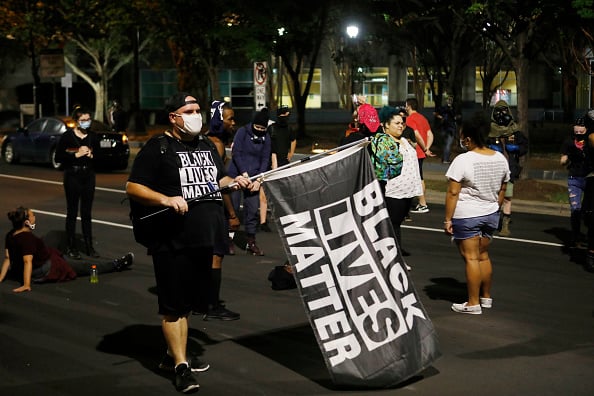 A man holding a Black Lives Matter flag while the Charlotte-Uprising activists disrupt traffic as they continue their protests this week in response to the Republican National Convention on August 27