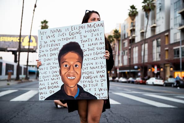 A person holds a sign at a candlelight vigil to demand justice for Elijah McClain on the one year anniversary of his death at The Laugh Factory on August 24