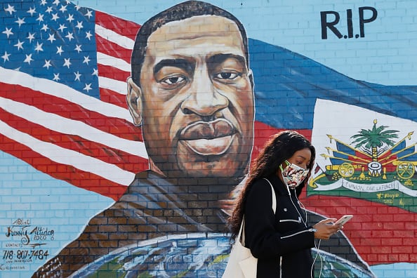A pedestrian walks past a mural painted by artist Kenny Altidor depicting George Floyd on a sidewall of CTown Supermarket on March 9