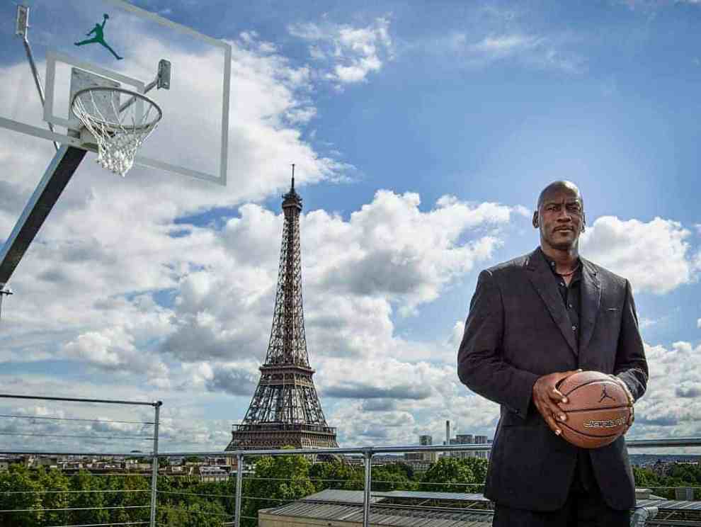 Michael Jordan holding basketball in front of net and the Eiffel Tower