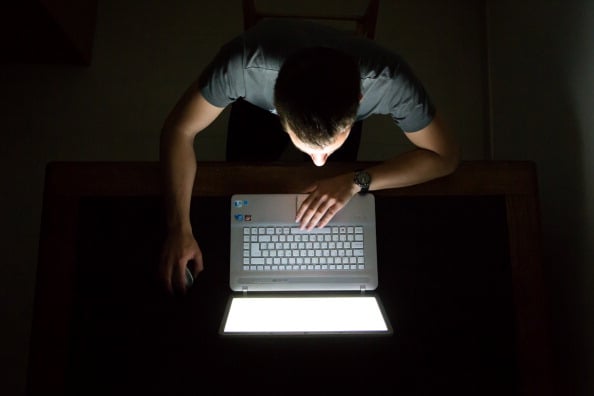 Guy checking internet with laptop at late night with dark room