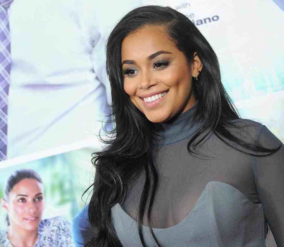 Lauren London wearing grey and white and smiling at the camera