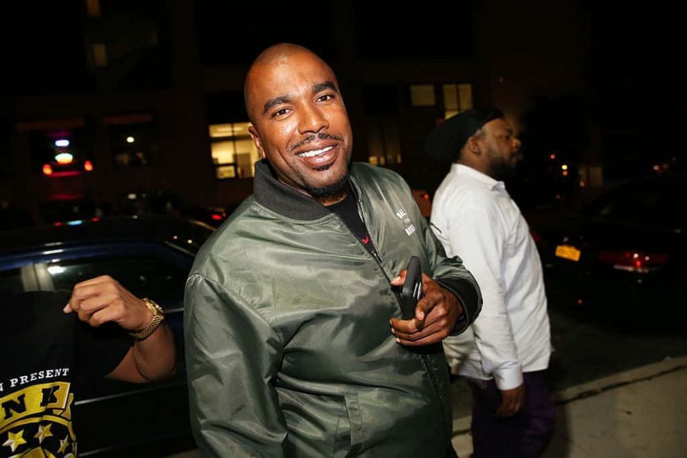 N.O.R.E wearing a green jacket smiling at the camera