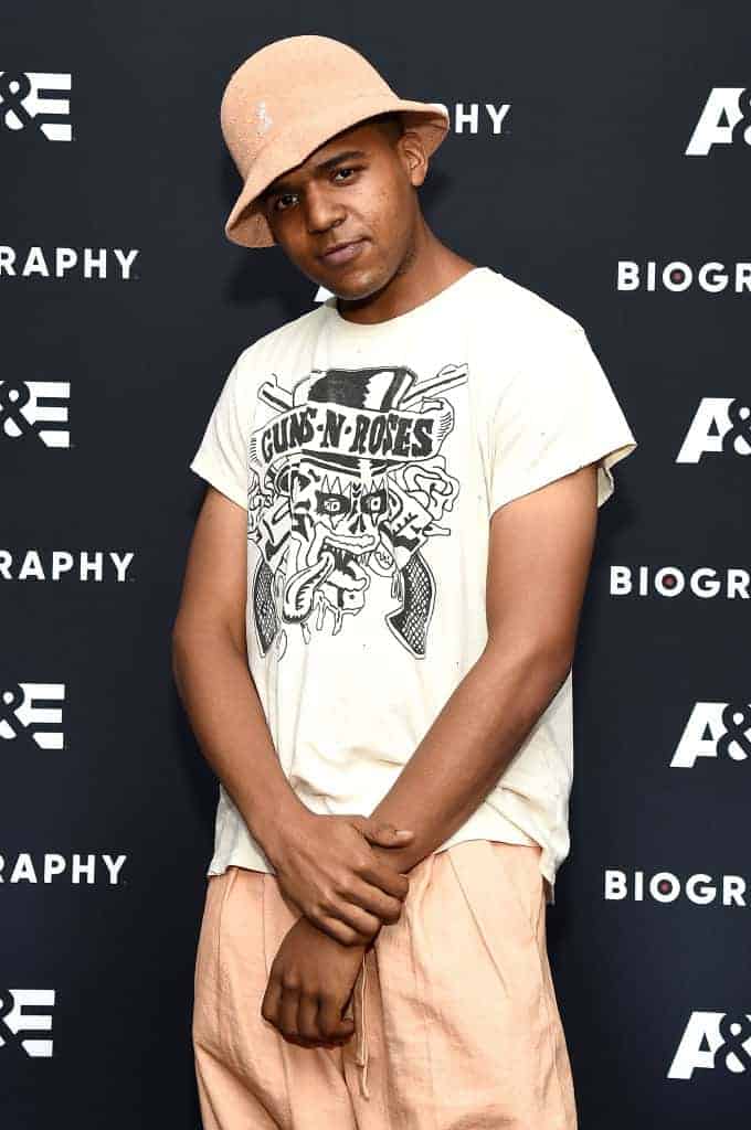 CJ Wallace wearing a bucket hat and white shirt with peach pants