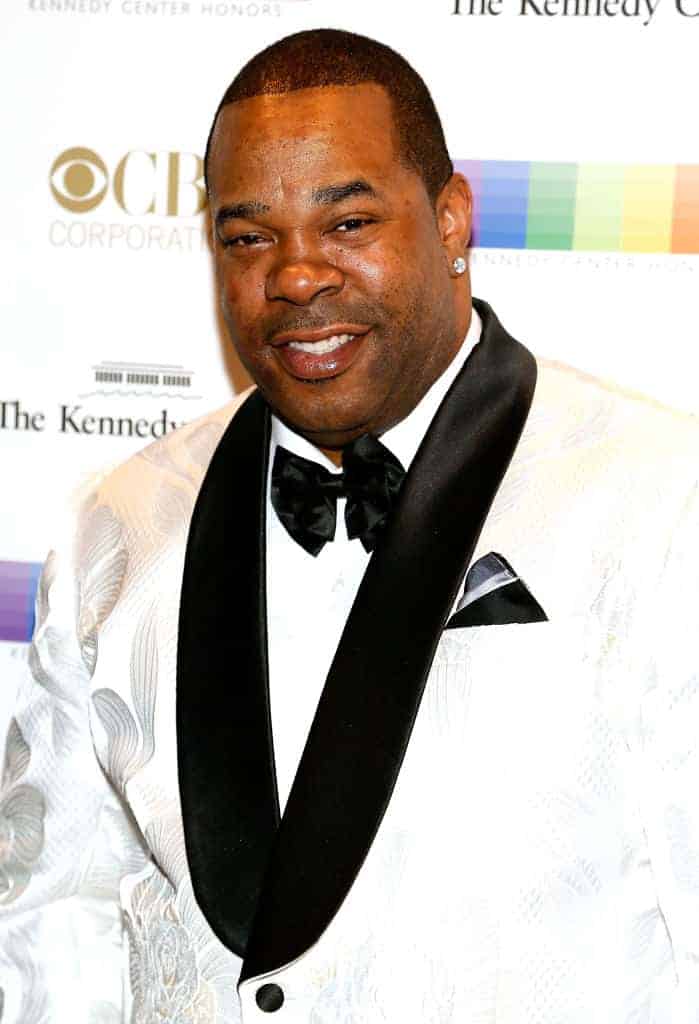 Rapper Busta Rhymes on the red carpet posing for a picture wearing a white and black suit.