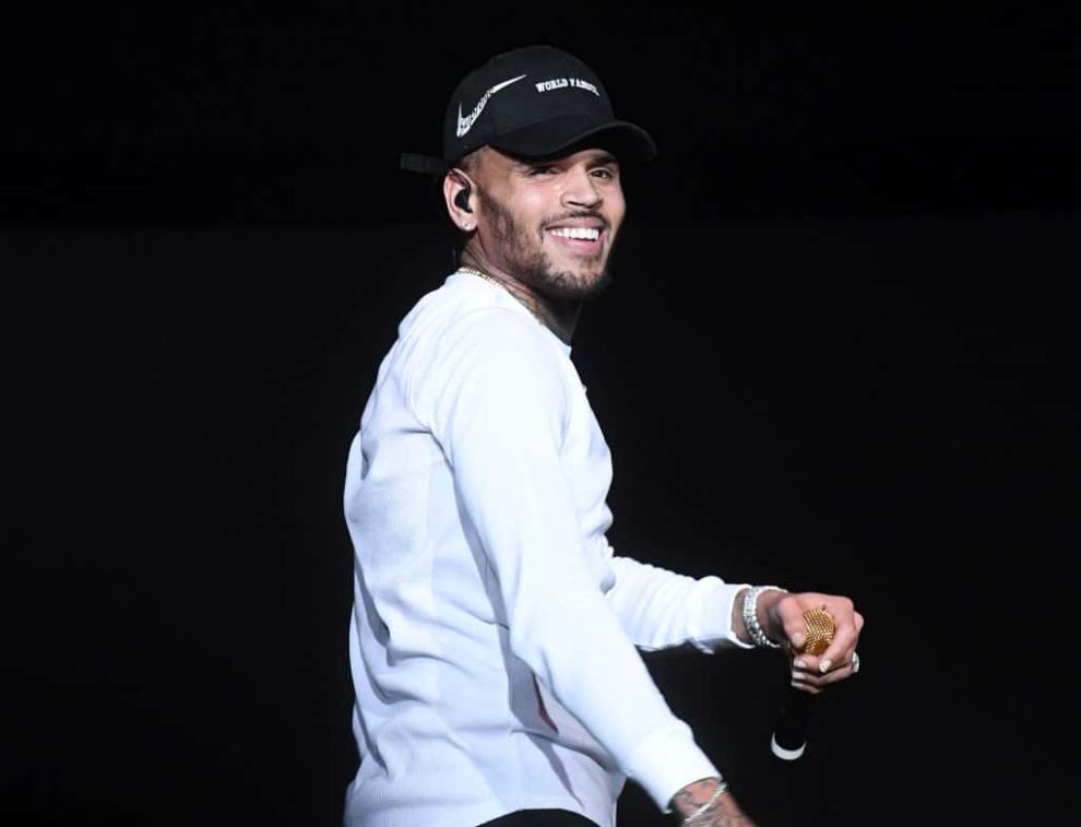 Chris Brown wearing a white shirt and black hat