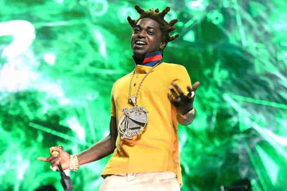 Kodak Black standing on stage with a yellow shirt on