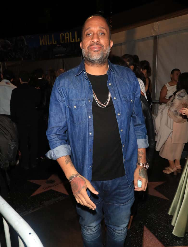 Kenya Barris standing wearing blue and black shirt and blue jeans