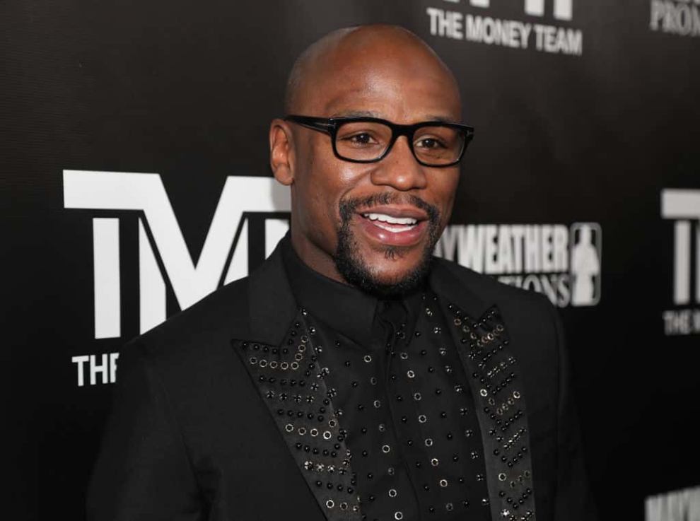Floyd Mayweather wearing all black standing in front of a black and white background