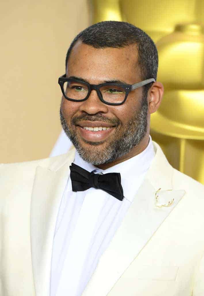 Jordan Peele wearing a white suit and black bow tie