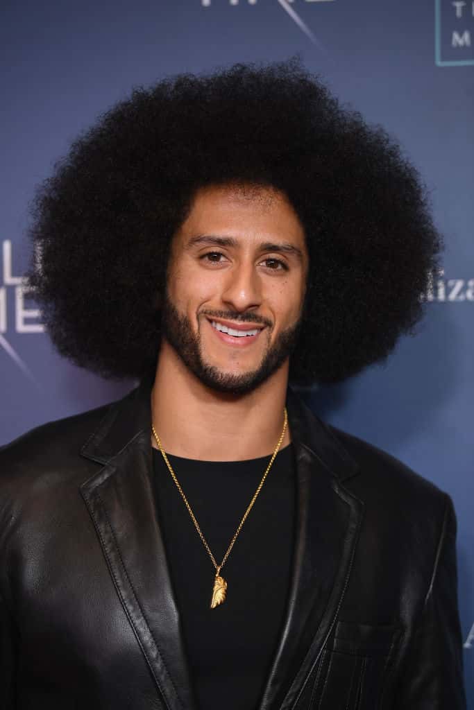 Colin Kaepernick wearing all black and smiling at the camera