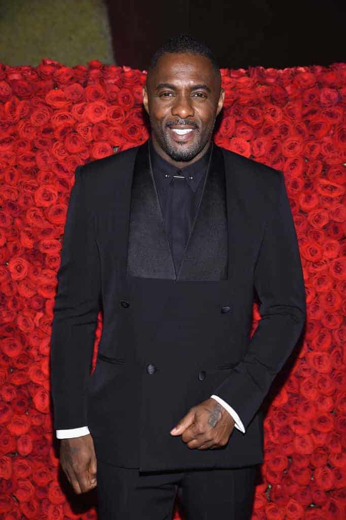 Idris Elba in front of wall of red roses