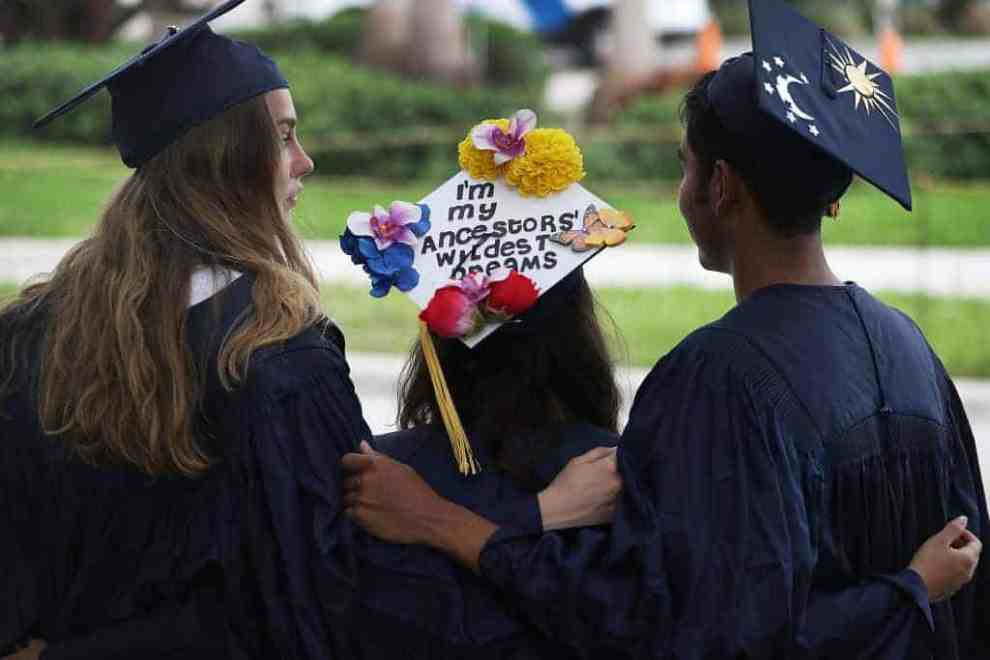 Three college graduates standing together after graduation with their cap and gown on